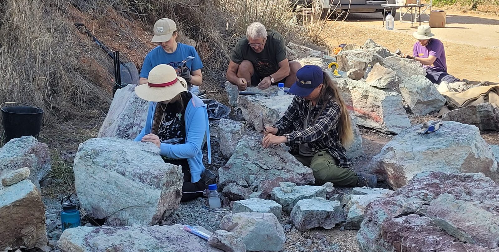 5 team members kneeling among large pale blocks, splitting them with hammers and chisels