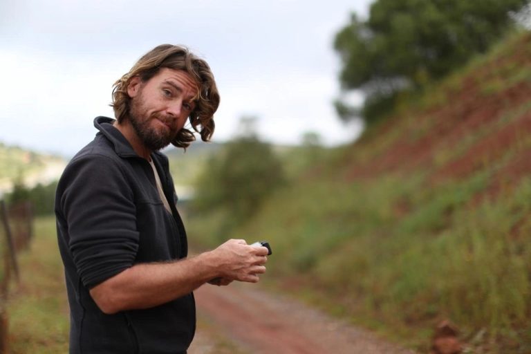 Expedition member on a dirt road beside a grassy slope