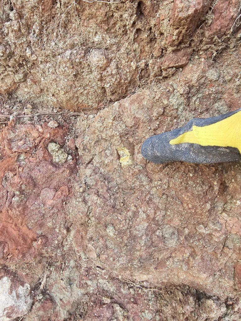 Boot beside mottled red and grey rock at the outcrop