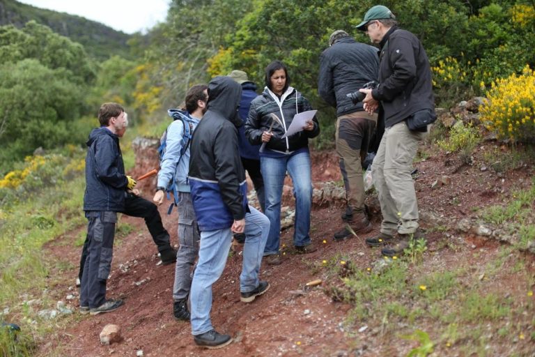 Team members gathered on a hillside reviewing notes