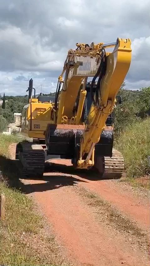 Excavator on a dirt track below the dig