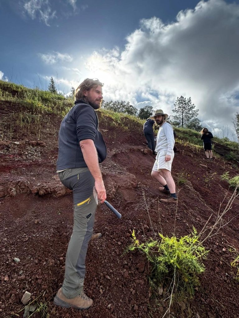 Team members walking the dig slope under a bright sky