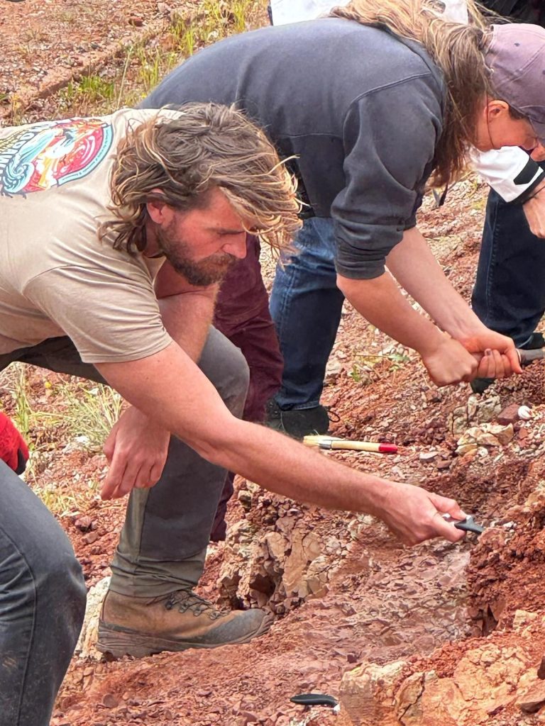 Team members looking closely at the rock surface