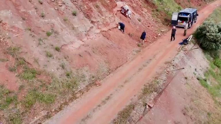 Aerial view of team members along a red rock slope and dirt road