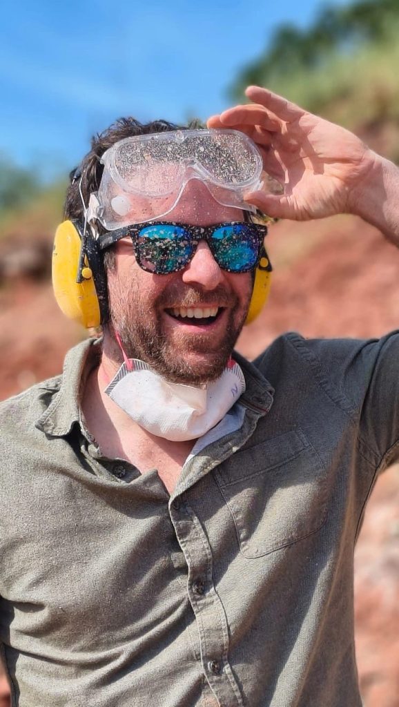 Team member in safety glasses and ear protection, laughing