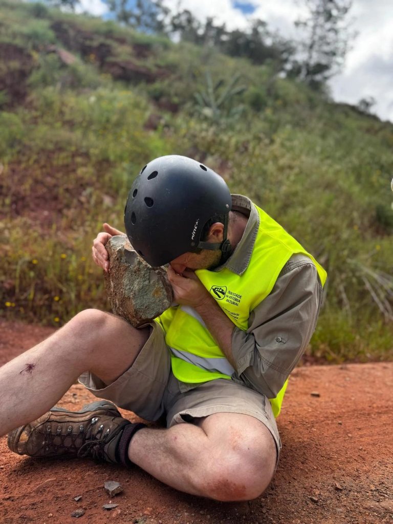 Team member in a helmet looking closely at a rock