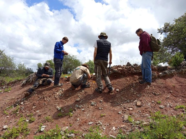 Team members prospecting on a stony hilltop