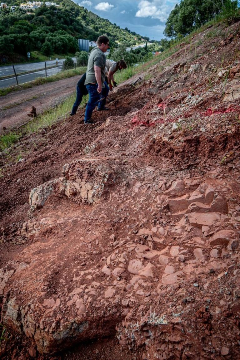 Team member on a steep slope of broken red rock