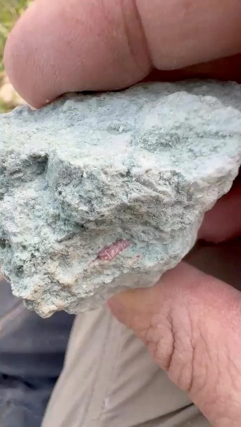 Close view of a pale green rock sample in hand