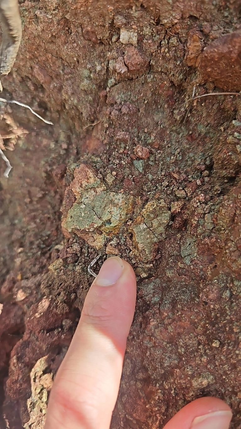 Finger pointing to a small fragment in red rock