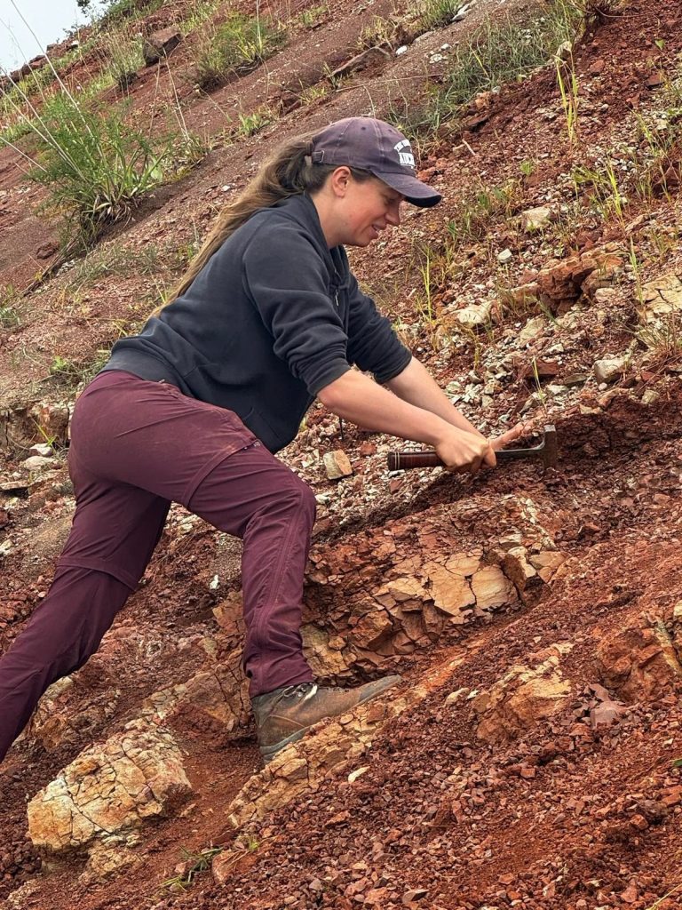 Team member climbing a steep red slope