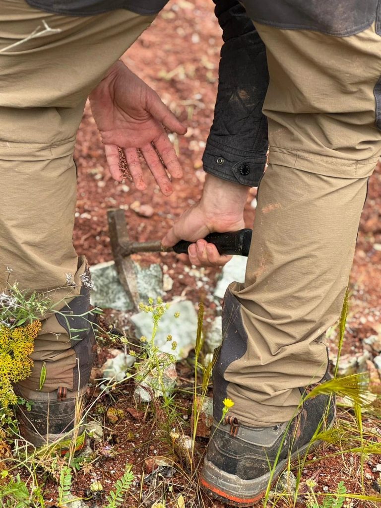 Team member splitting a rock with a hammer at their feet